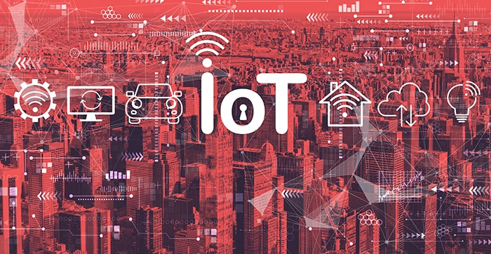 Letters IoT over a red city background